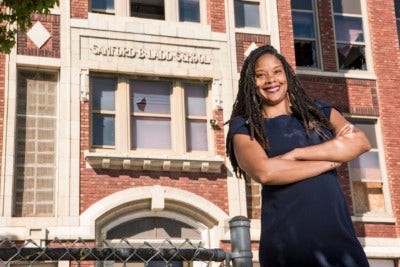 Ajia Morris stands in front of the abandoned Sanford Ladd School in Kansas City's East Side, the site of a redevelopment that prioritizes local ownership.