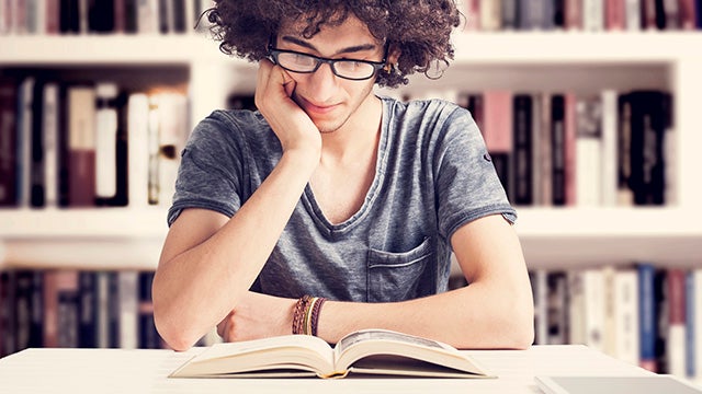 Young student reading book in library