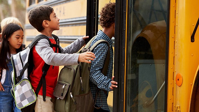 school kids climbing on to a school bus
