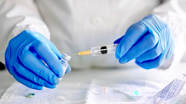 Hands filling a syringe